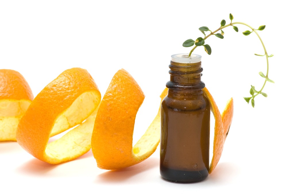 essential oil bottle with thyme and orange peel isolated on white